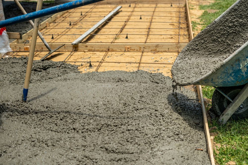 Wheelbarrow Pouring Wet Concrete Into a Wooden-Framed Construction Site — Wal's Concreting Service Pty Ltd in Kyogle, NSW