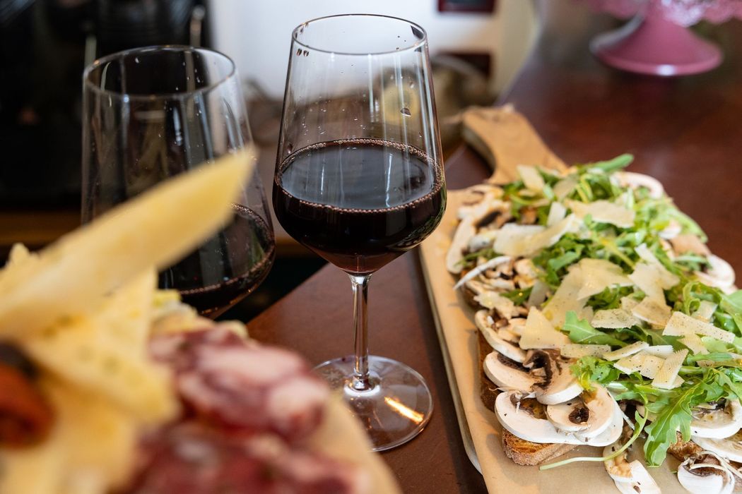 Bicchieri da vino e un piatto da insalata su un tavolo di un ristorante, con un cestino del pane sfocato in primo piano