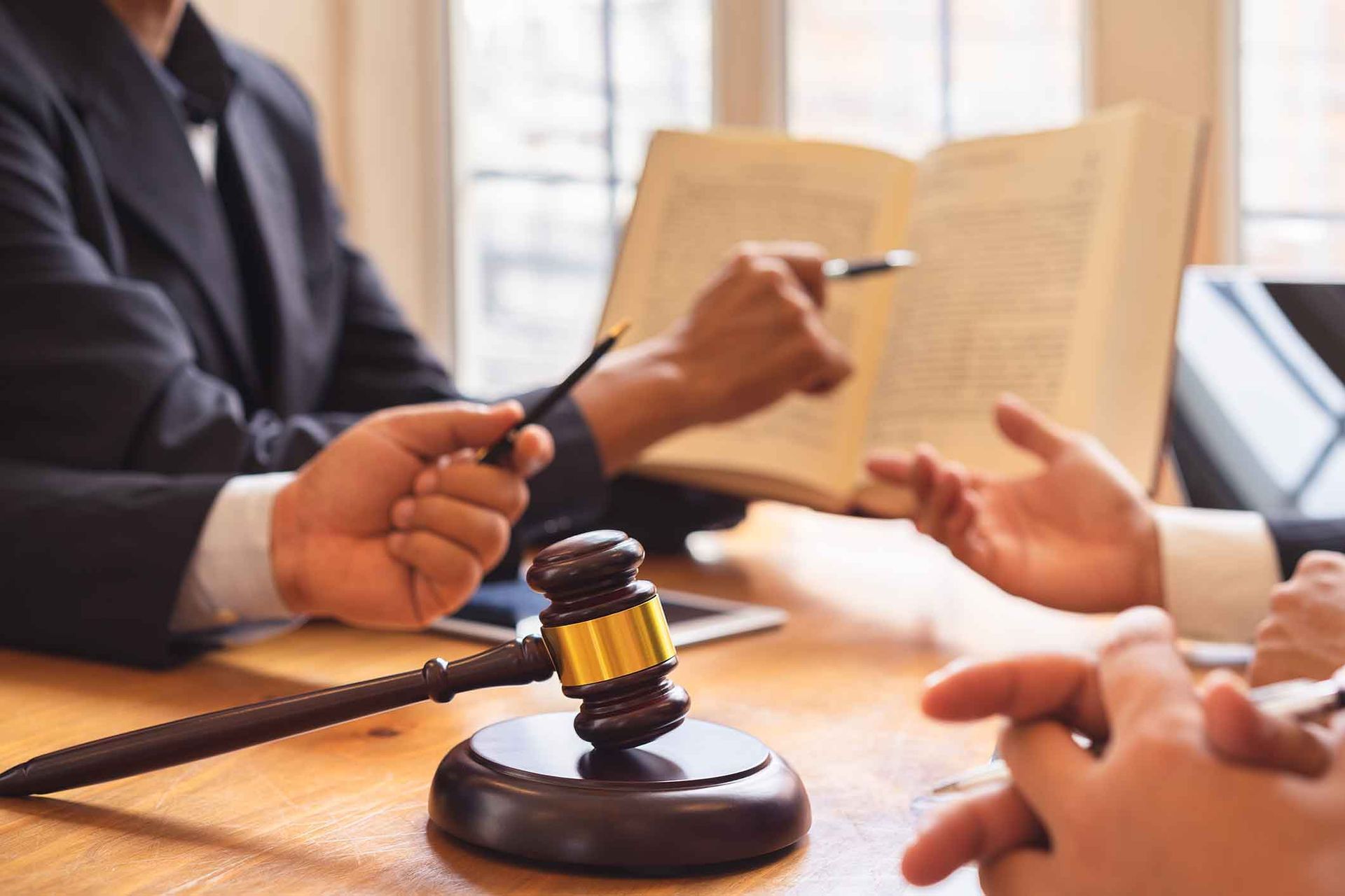 A group of people are sitting at a table with a judge 's gavel and a book.