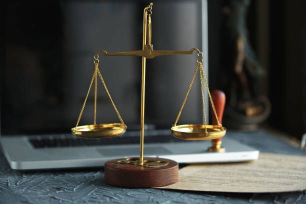 A scale of justice is sitting in front of a laptop computer.
