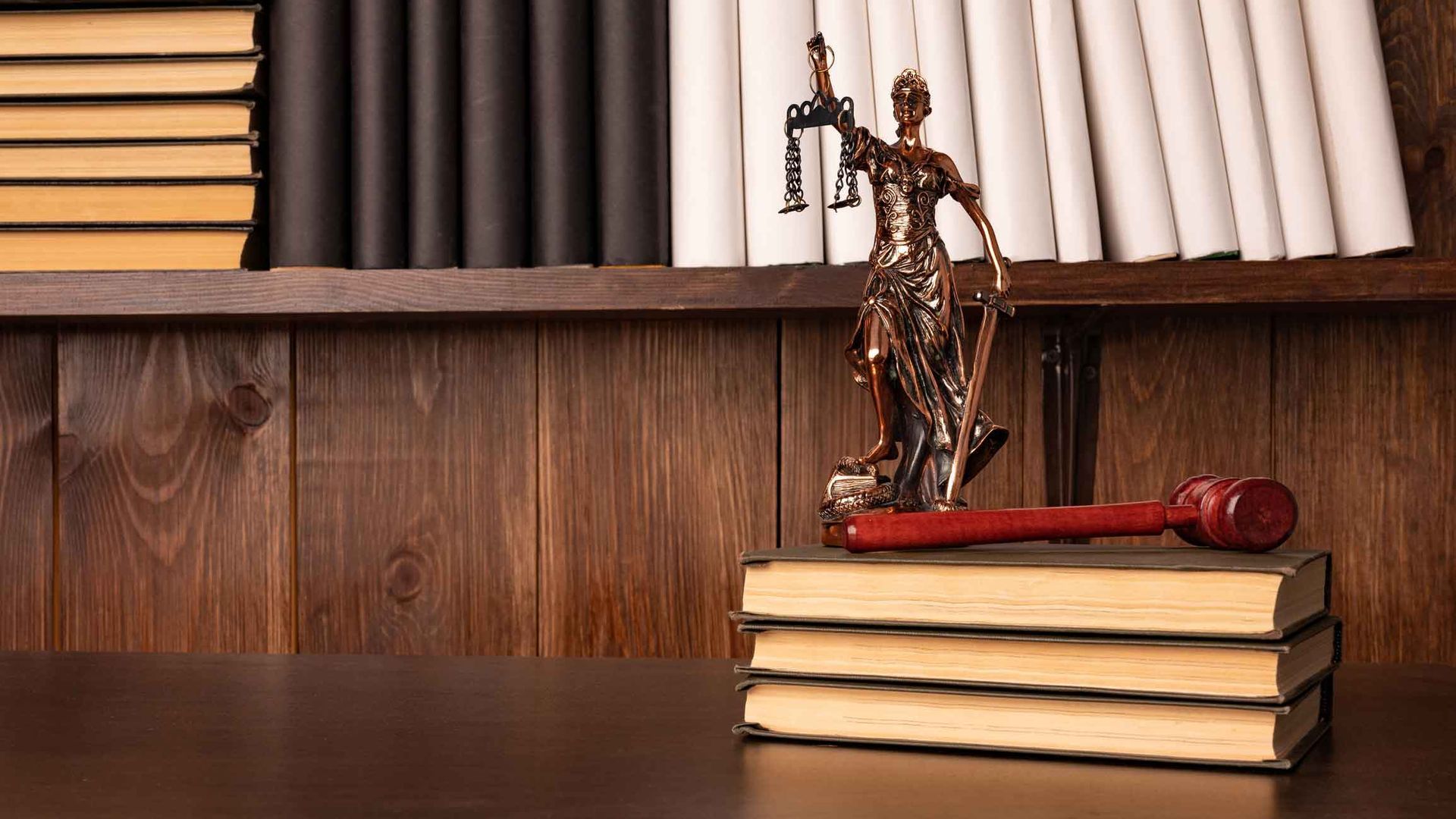 A statue of justice is sitting on top of a stack of books.