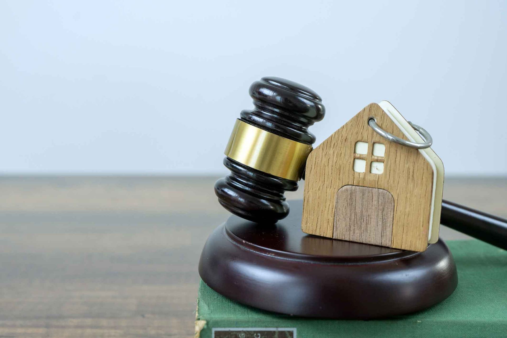 A wooden gavel with a model of a house on top of it.