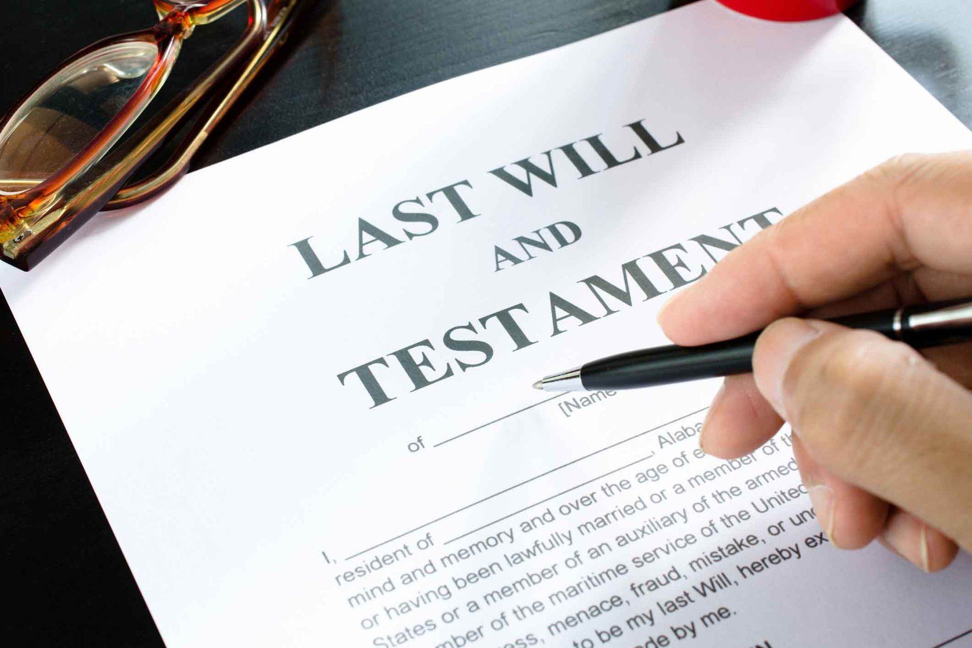 A person is signing a last will and testament with a pen.