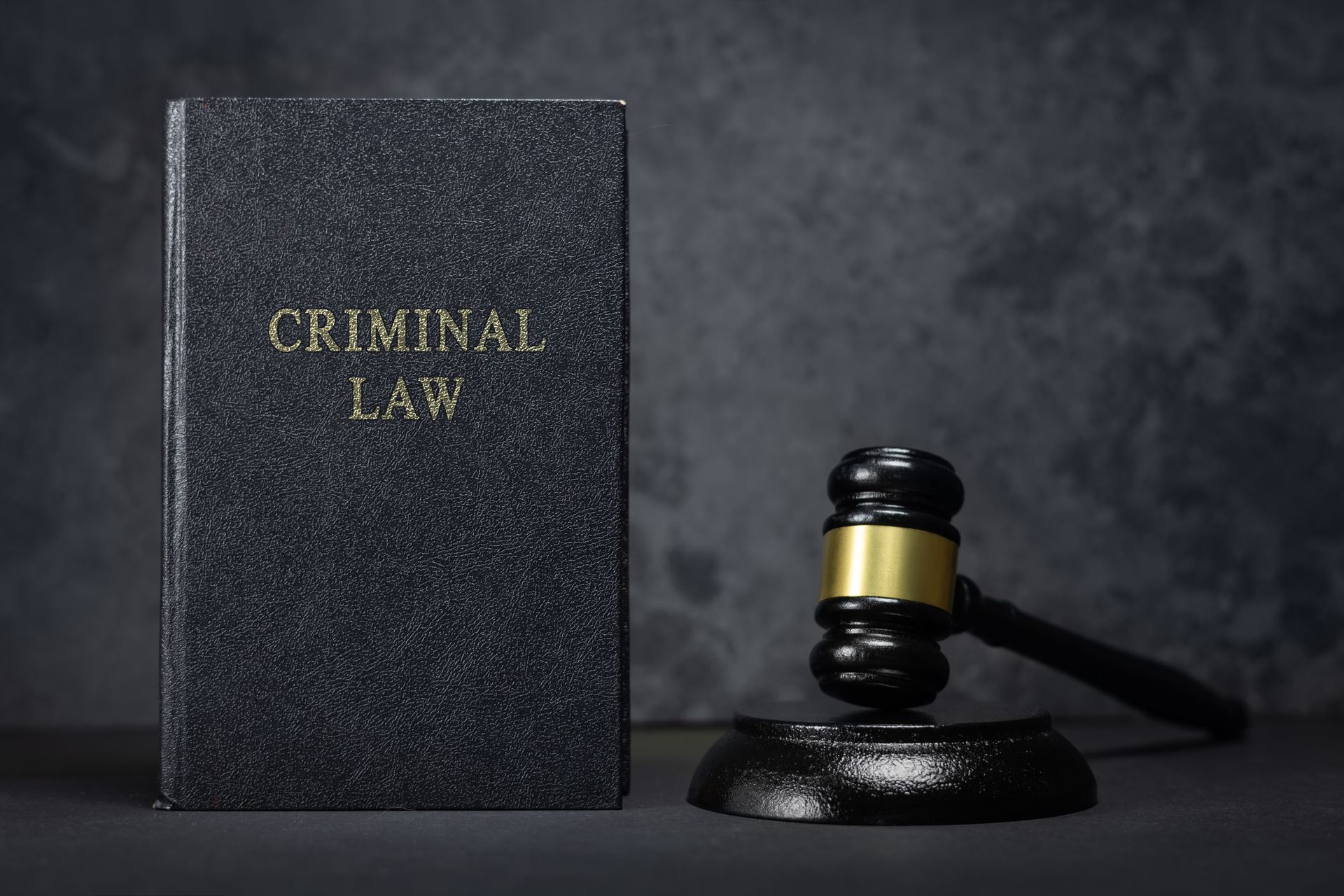 A judge's gavel and a book on criminal law on a grey background