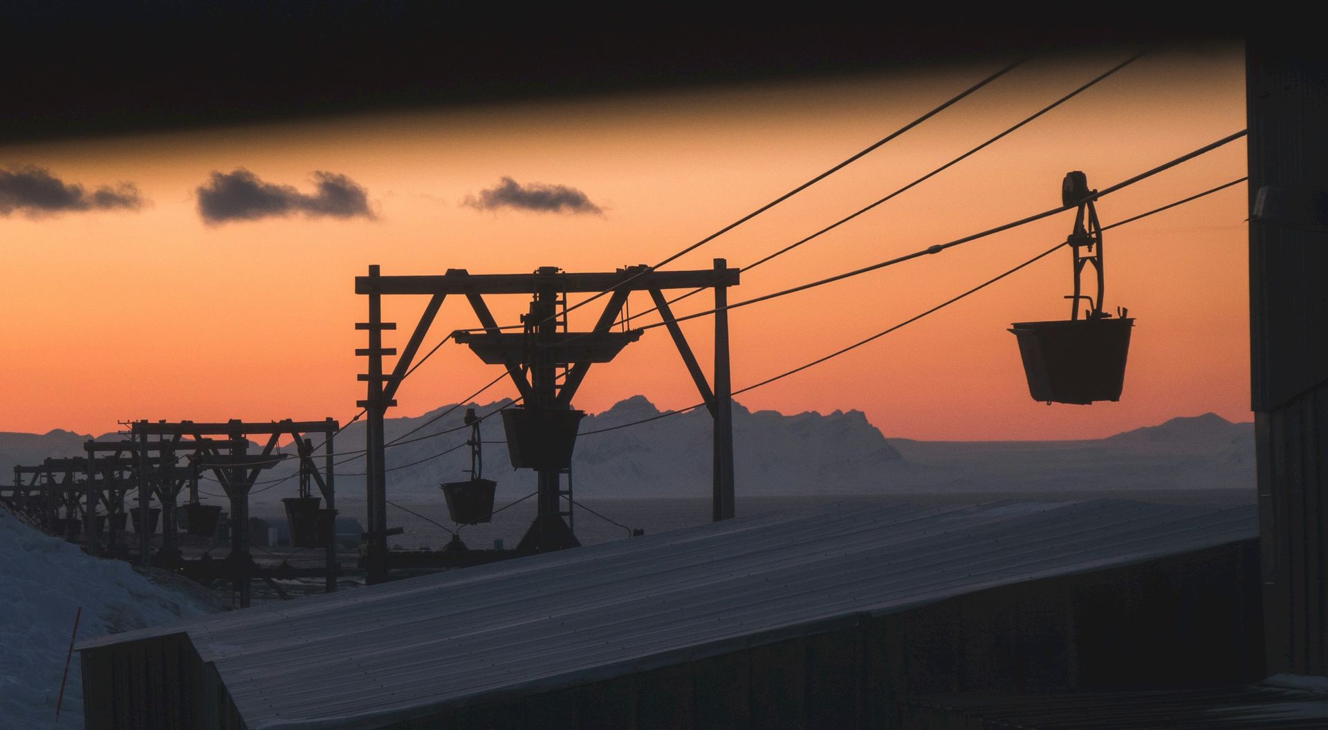 A ski lift is silhouetted against a sunset sky.