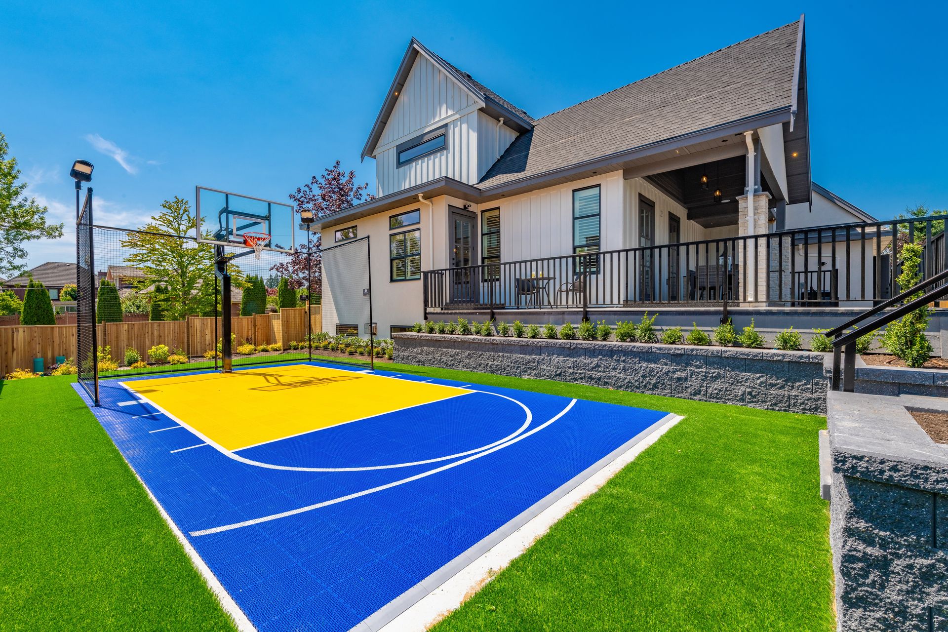 There is a basketball court in the backyard of a house.