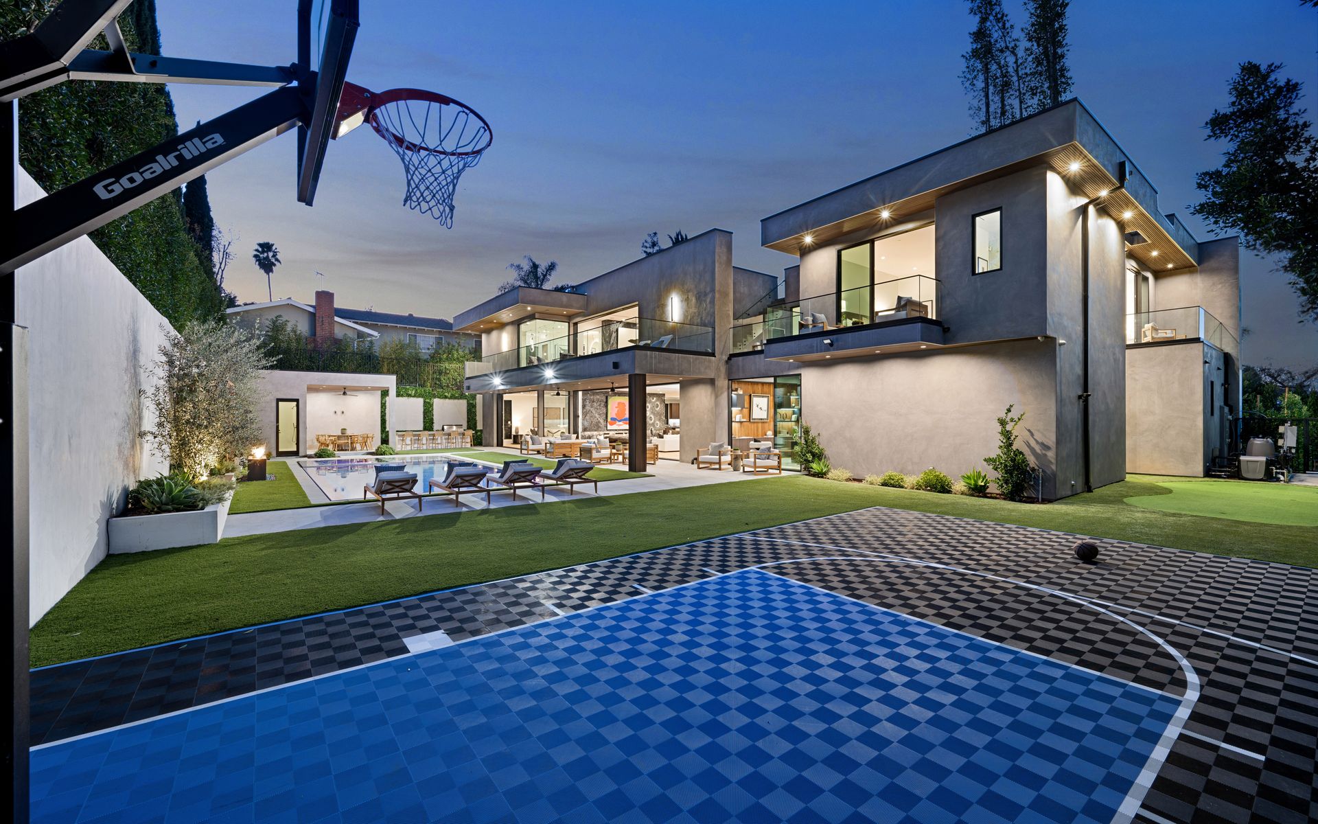 A large house with a basketball court in front of it.