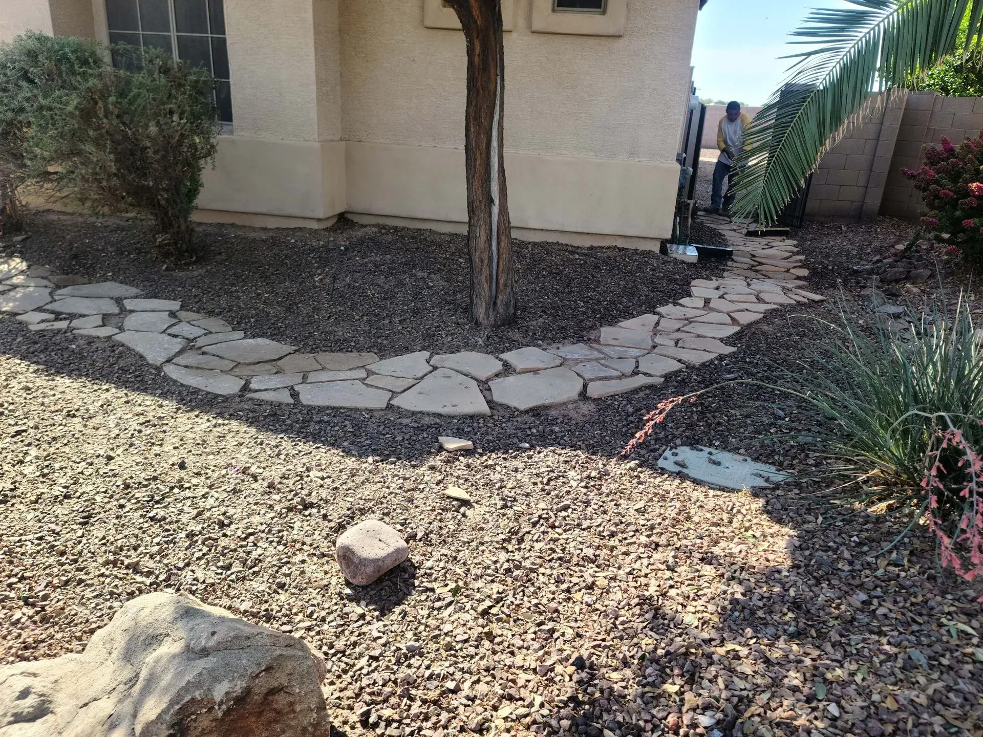 Rock garden beside a beige house with a curved stepping-stone path and desert plants
