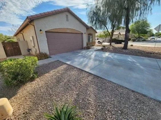 Suburban house with a two-car garage, concrete driveway, and desert landscaping in front yard