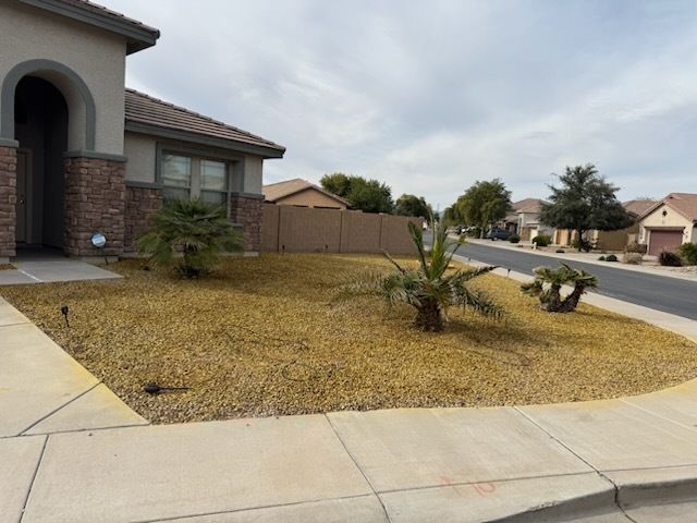 Person in yellow shirt planting a green shrub in a gravel yard