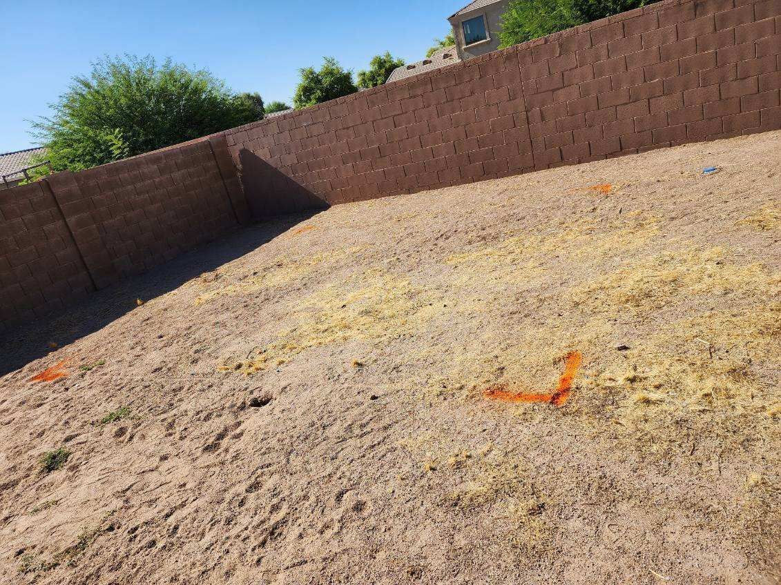Empty dirt yard enclosed by brick walls under a clear blue sky