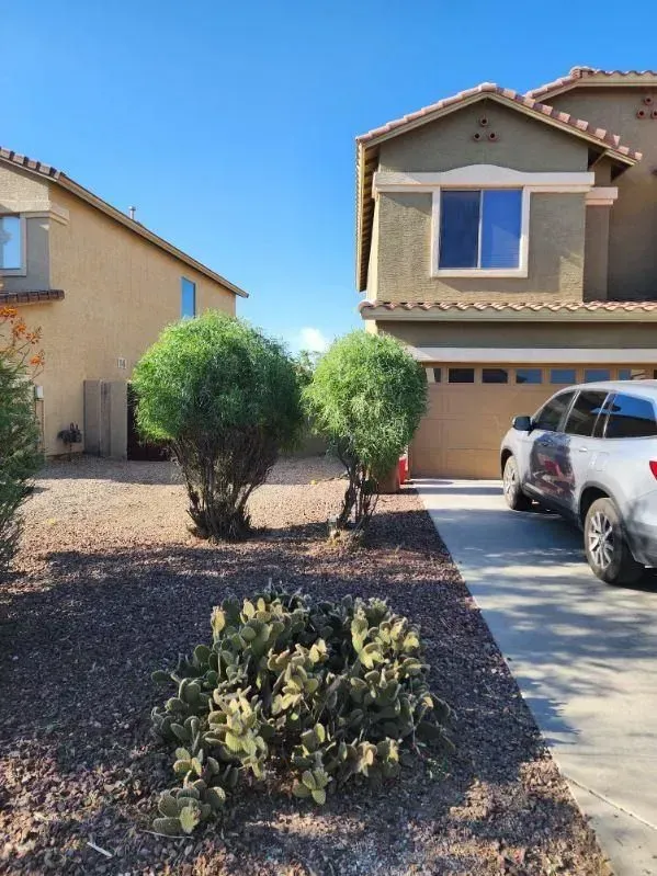 Suburban house with driveway, parked silver SUV, and desert landscaping under a blue sky
