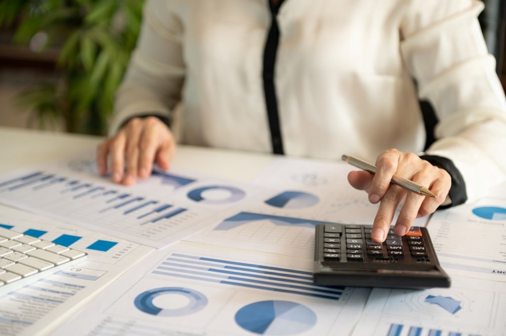 A Woman Is Sitting At A Table Using A Calculator — Tamworth Strata Management Services in Narrabri, NSW