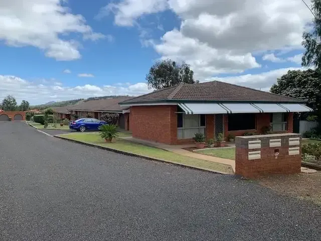A Blue Car Is Parked In Front Of A Brick House — Tamworth Strata Management Services in Narrabri, NSW
