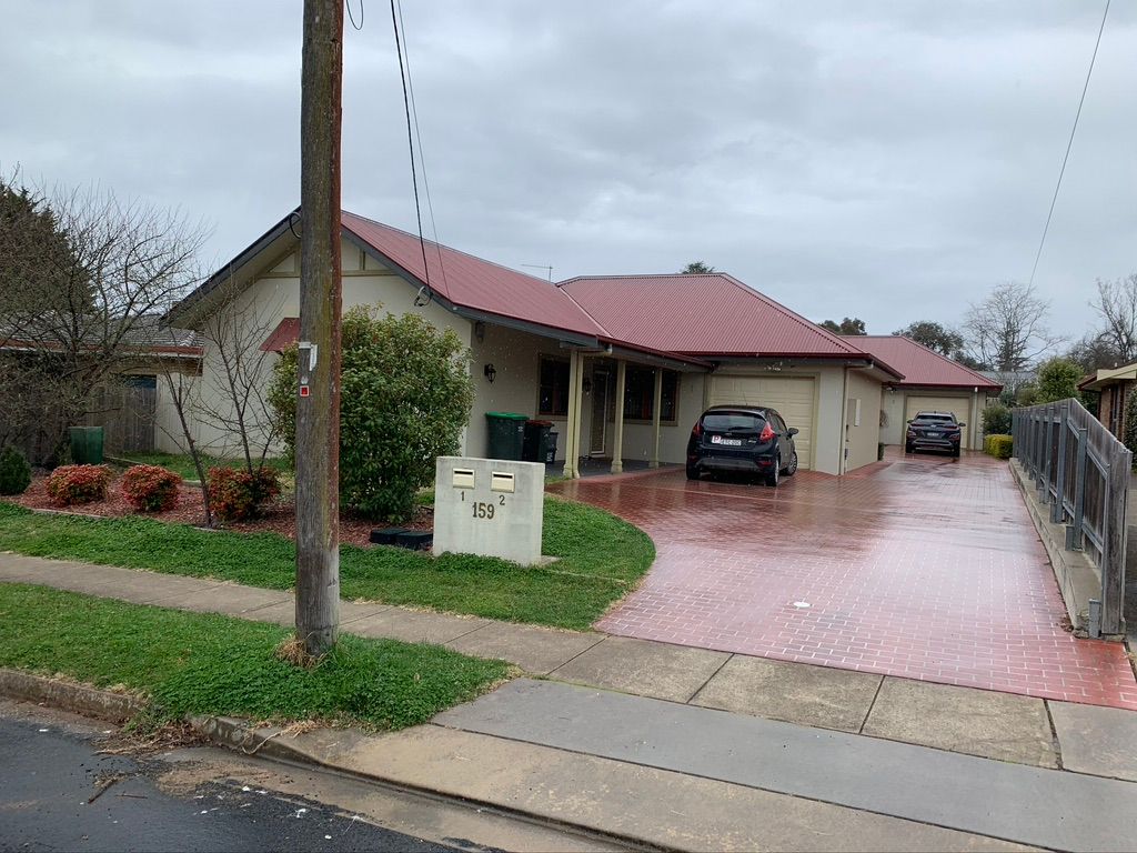 A residential building with red roof and driveway, a car parked in front on a cloudy day. — Tamworth Strata Management Services in Armidale, NSW