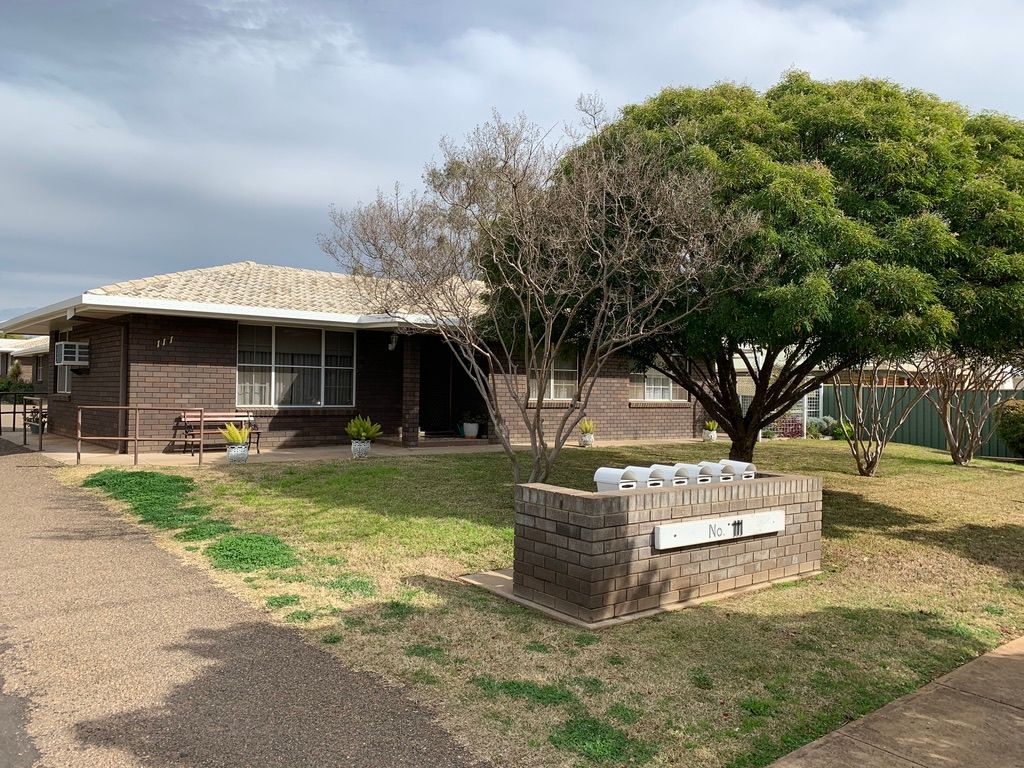 Brick apartments with a lawn, mailboxes, and trees under a cloudy sky. — Tamworth Strata Management Services in Gunnedah, NSW