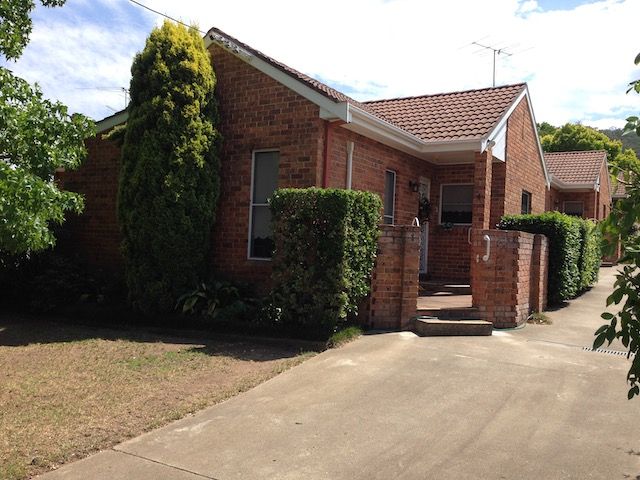 Brick townhouses with red tile roofs and a shared driveway; exterior view. — Tamworth Strata Management Services in Tamworth, NSW