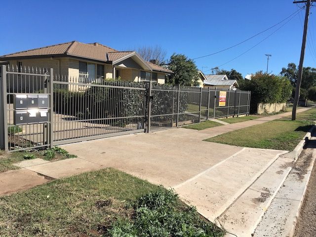 Gray gated house with mailbox, sidewalk, and green lawn on a sunny day. — Tamworth Strata Management Services in Gunnedah, NSW