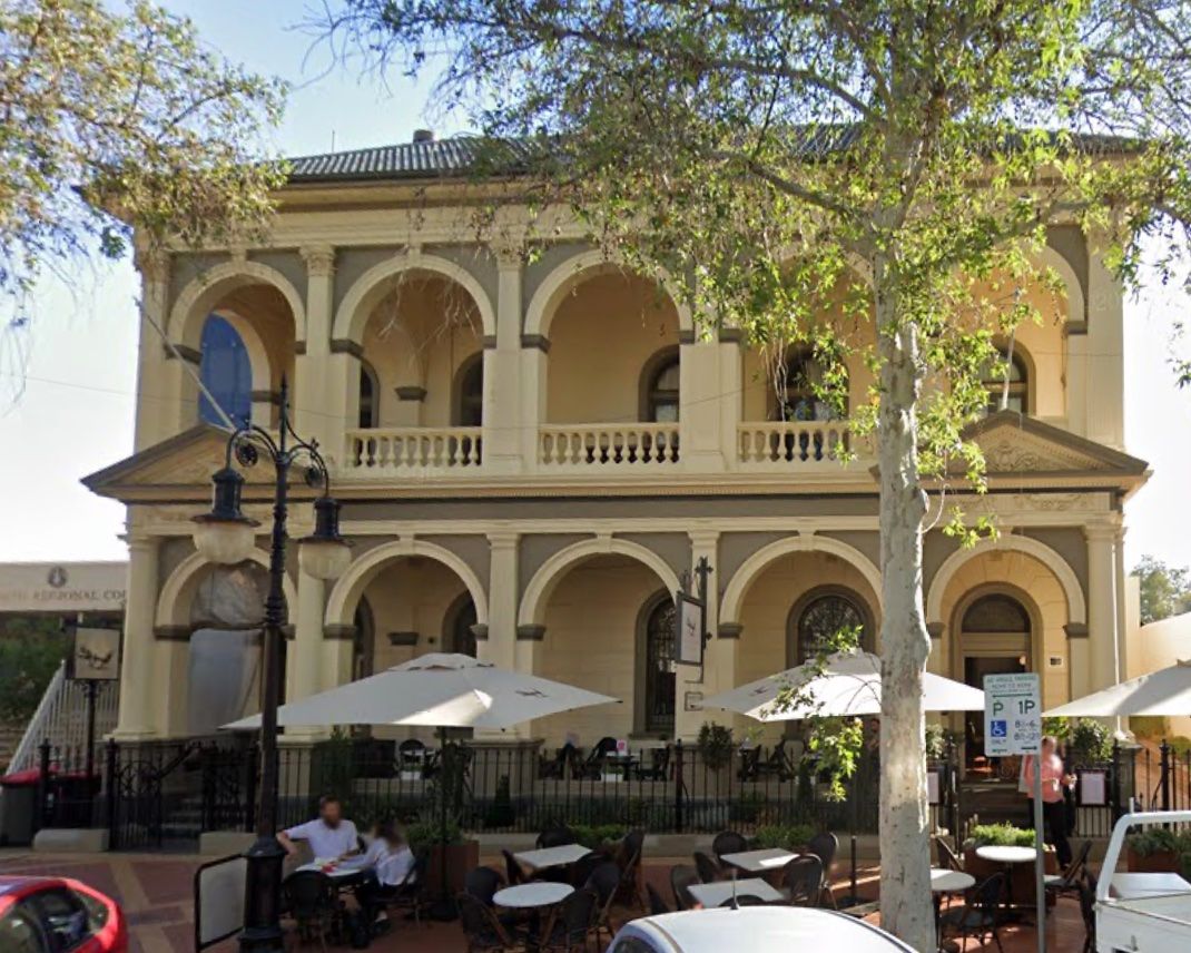 Two-story building with arched windows and outdoor seating, possibly a restaurant. — Tamworth Strata Management Services in Tamworth, NSW