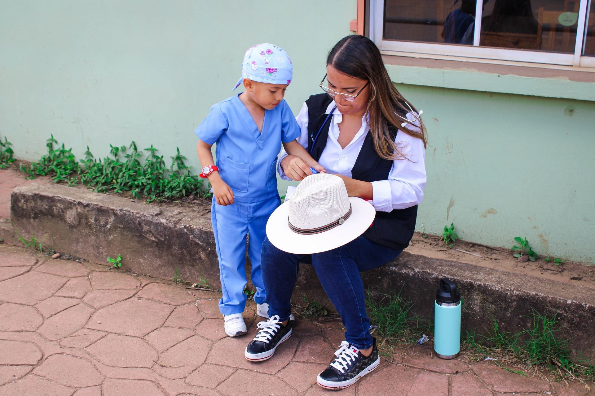 A woman is sitting next to a child wearing a hat.