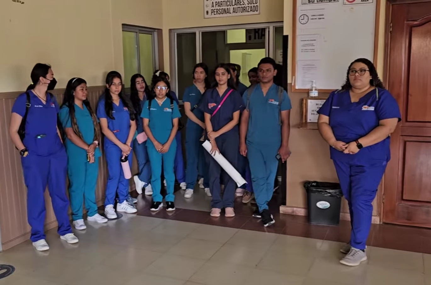 Medical staff in scrubs stand in a hospital hallway.