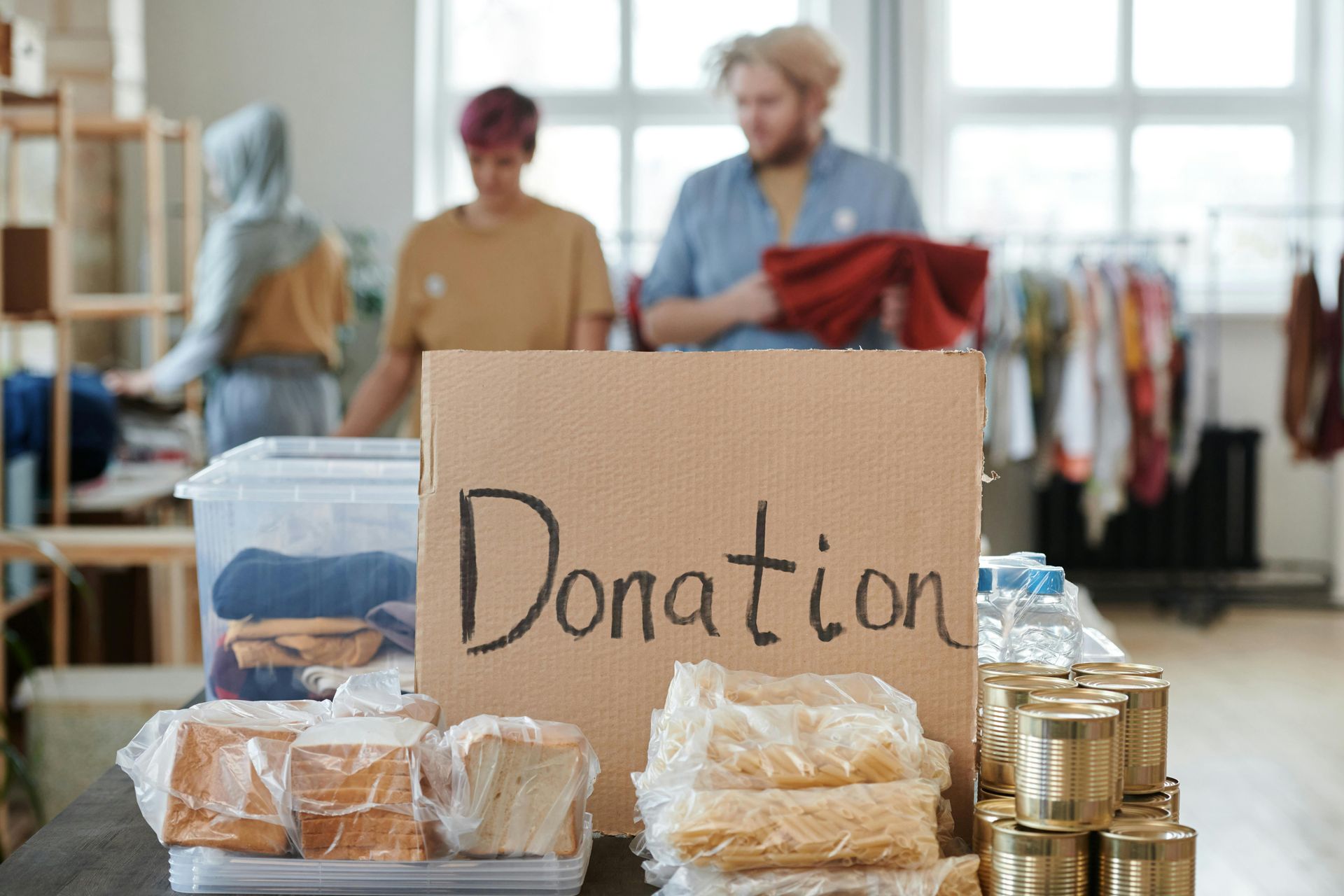 Donation box with food and people sorting donations in the background.