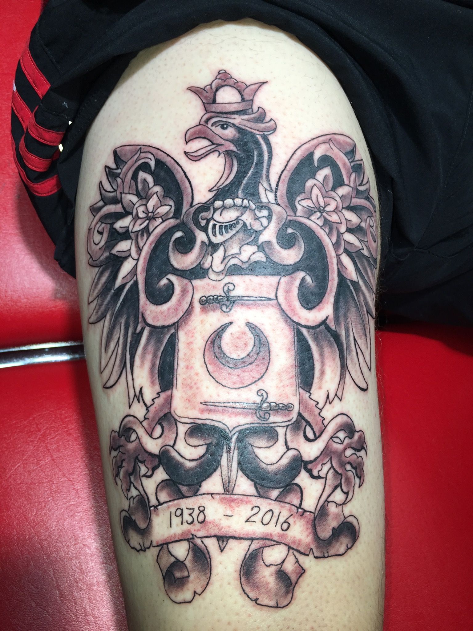A person has a tattoo of a coat of arms on their leg