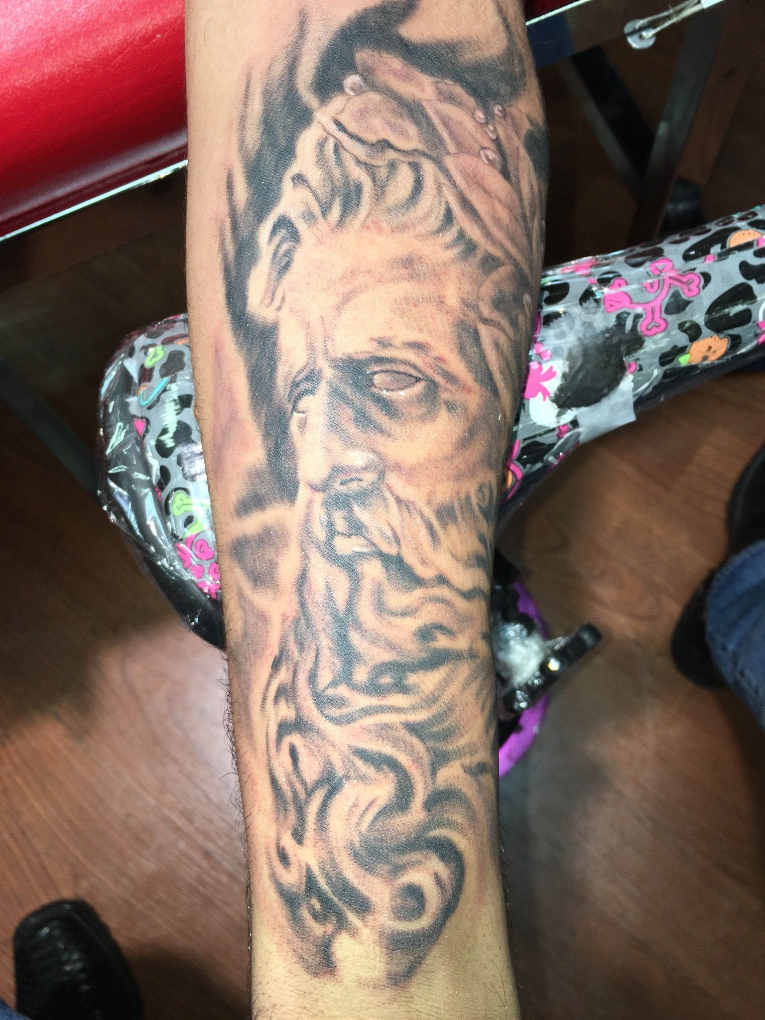 A person has a tattoo of a man with a beard on their arm.
