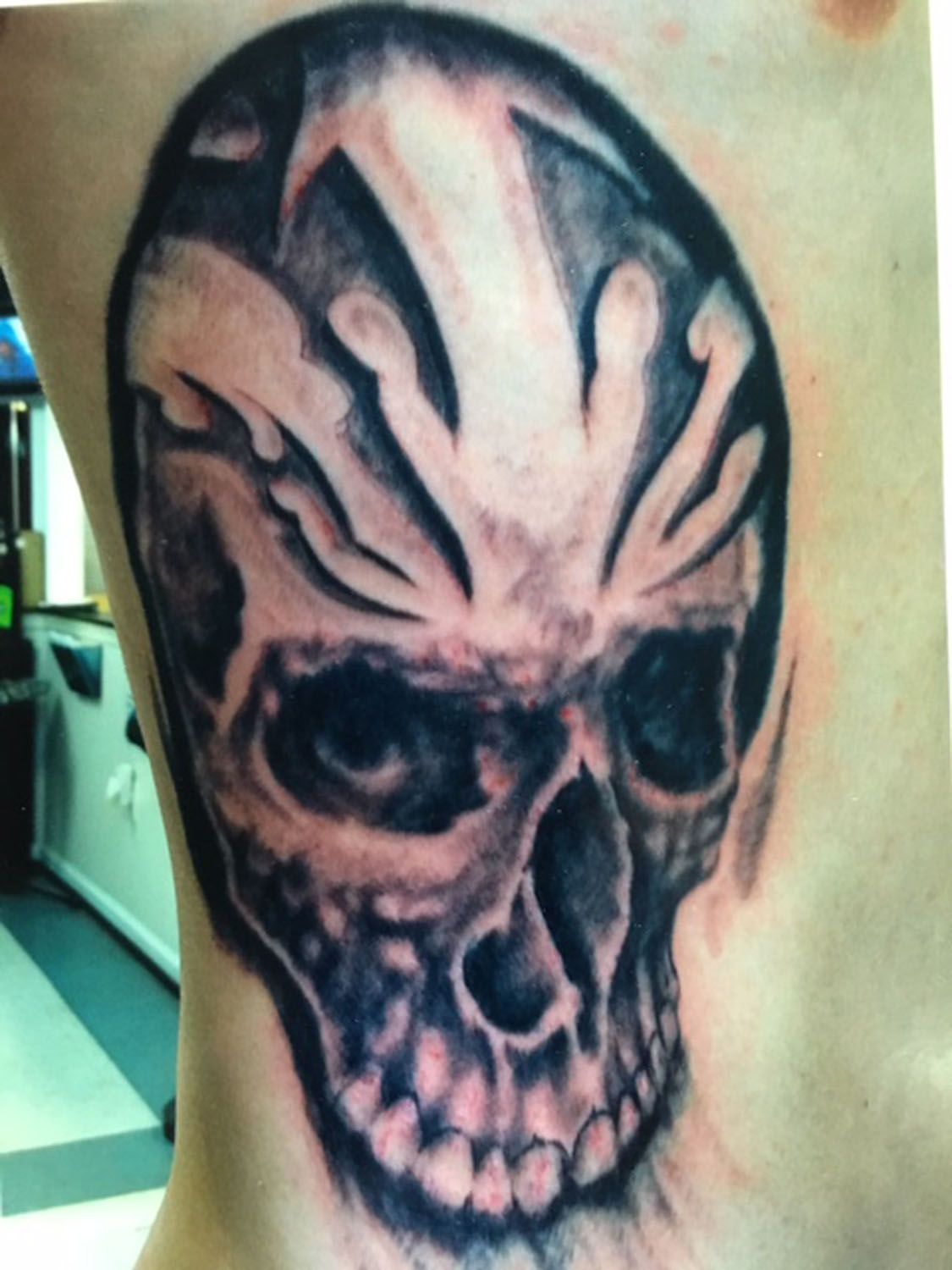 A man has a tattoo of a skull on his side