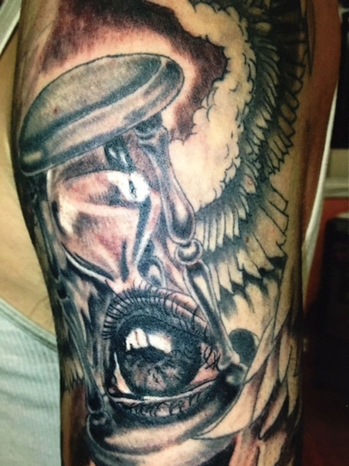 A black and white tattoo of a hourglass and an eye