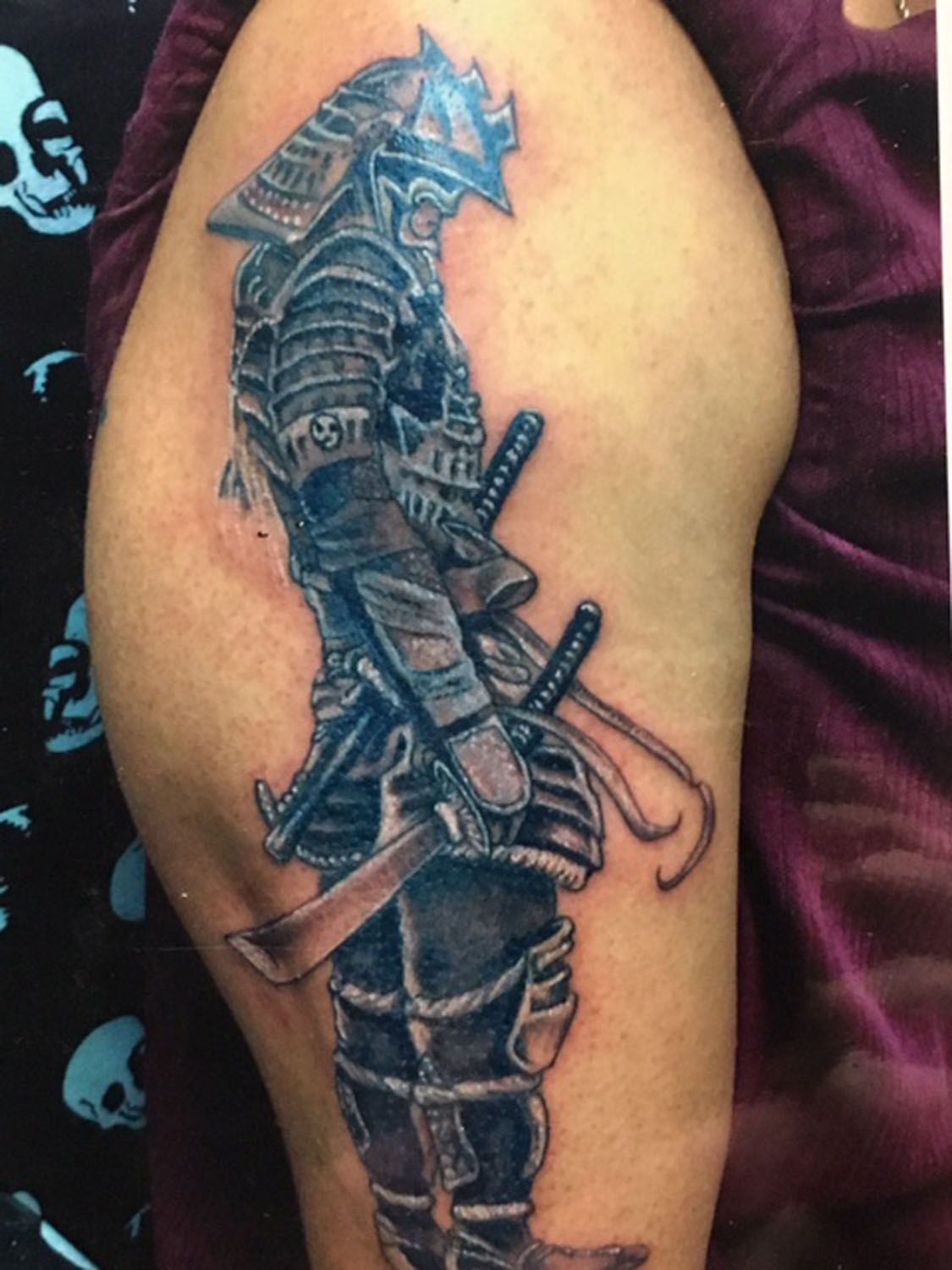 A person has a tattoo of a samurai on their arm