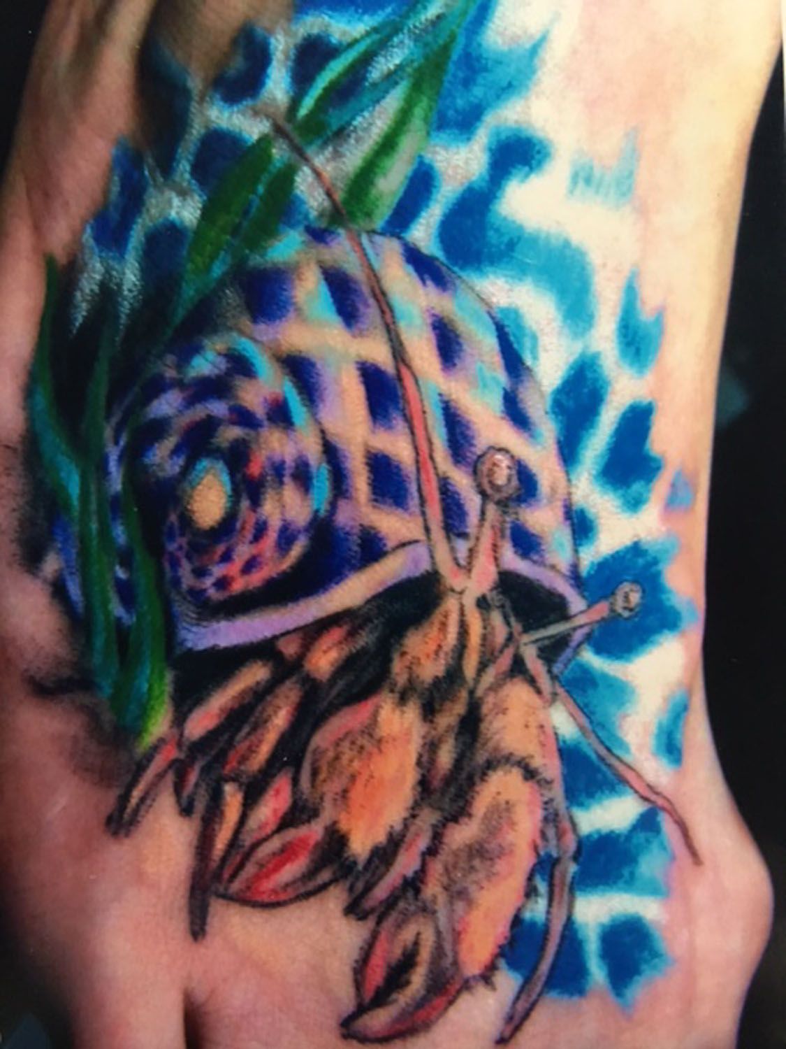 A close up of a hermit crab tattoo on a person 's arm