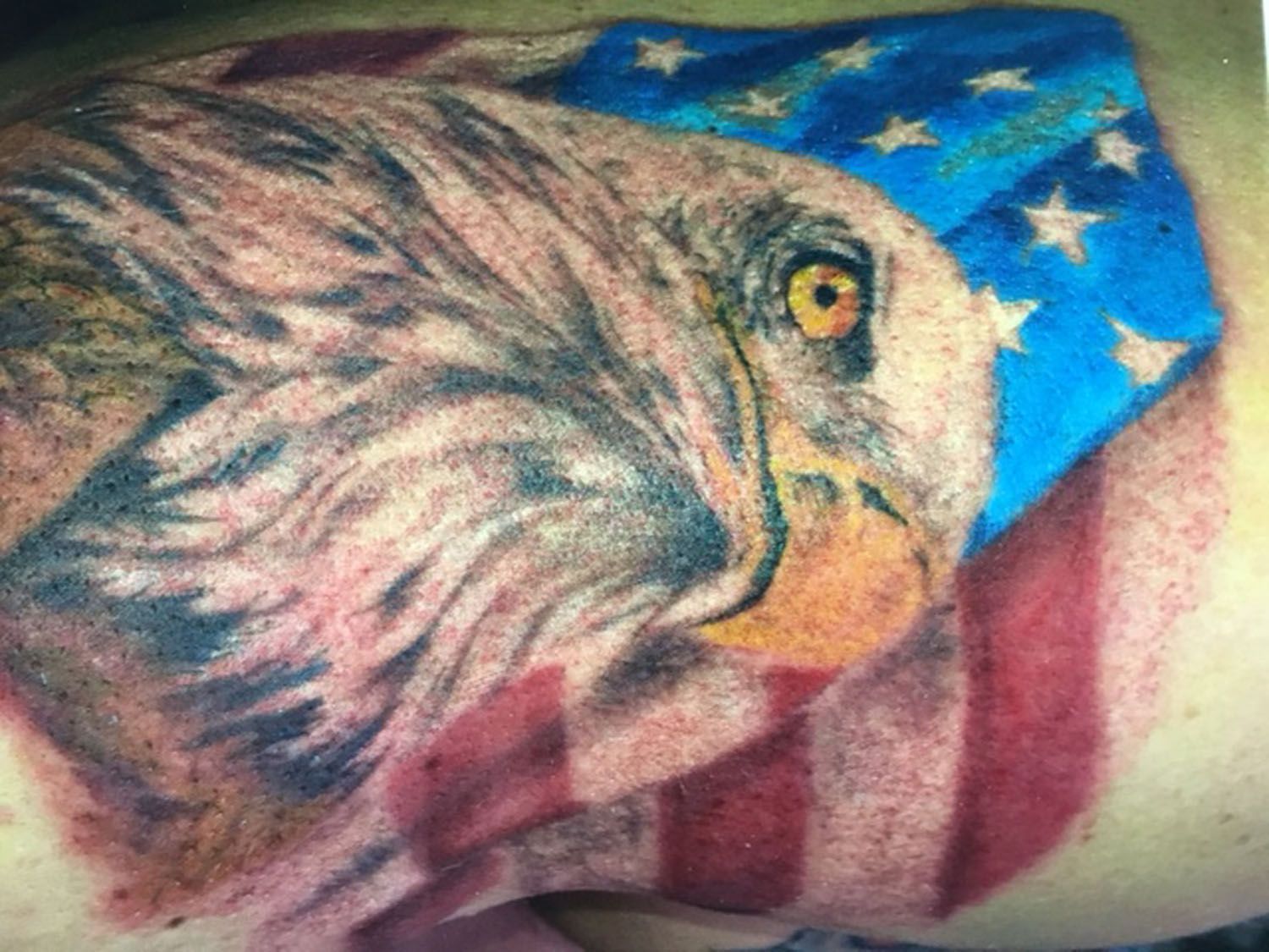 A bald eagle with an american flag tattoo on a person 's arm.