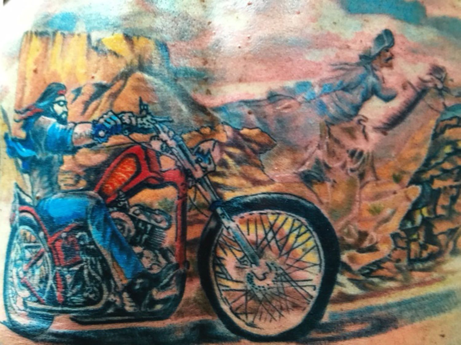 A man has a tattoo of a man riding a motorcycle