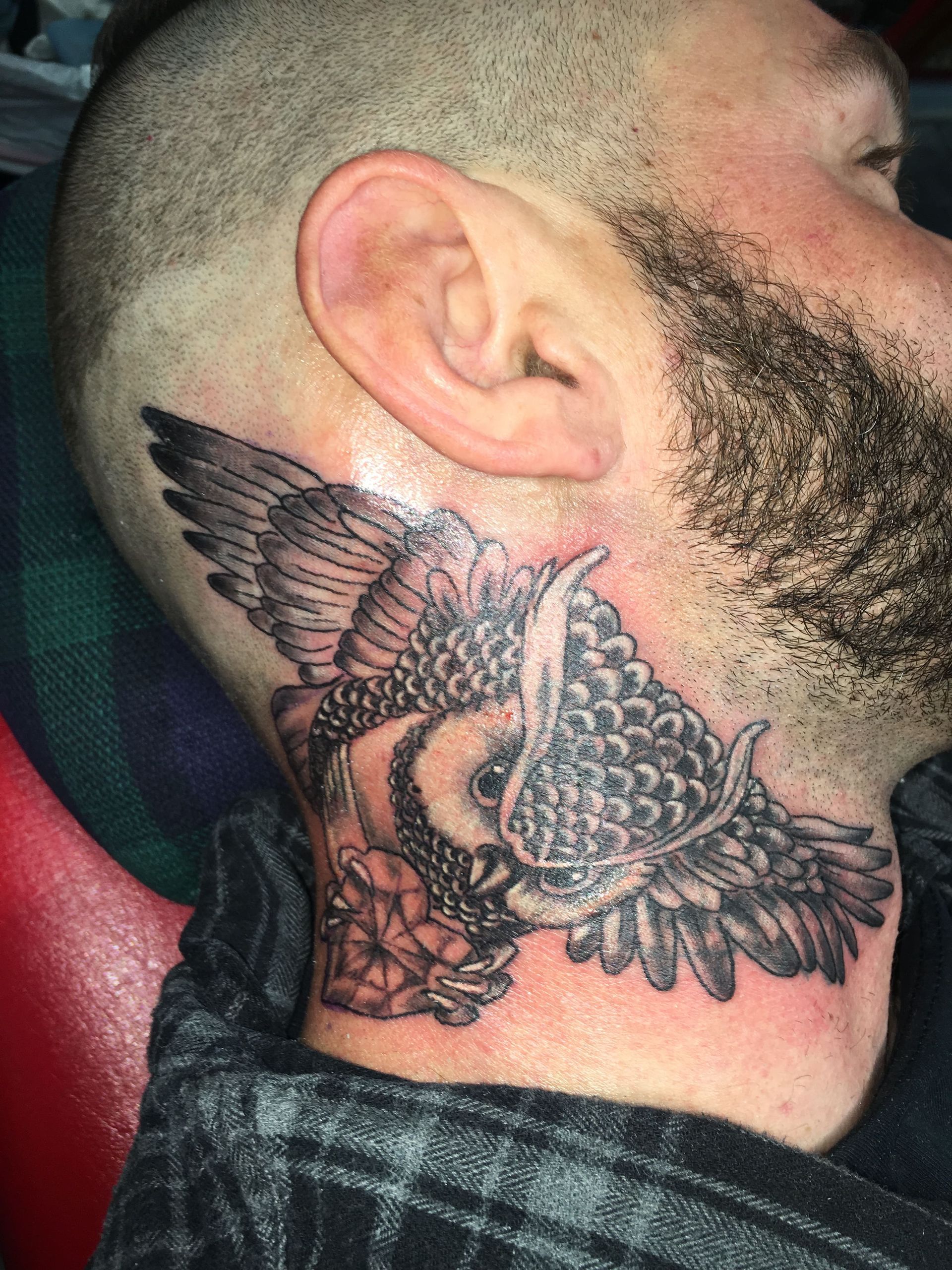 A man has a tattoo of an owl on his neck