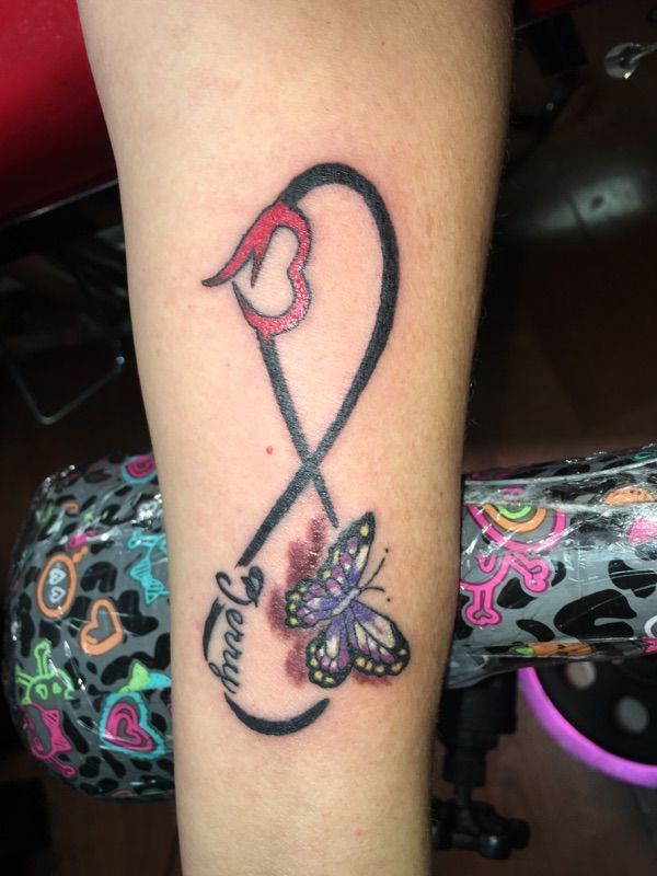 A tattoo of an infinity symbol with a butterfly and the name jenny