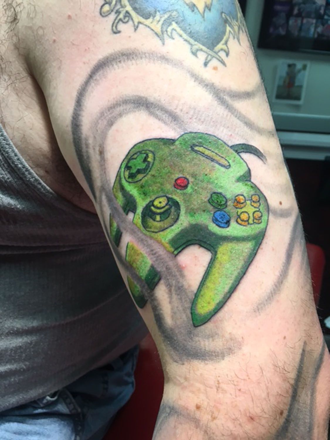 A man has a tattoo of a video game controller on his arm.