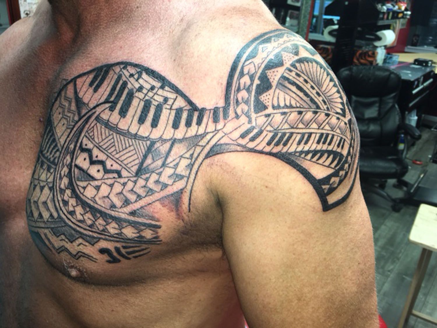 A man has a tattoo on his chest and shoulder