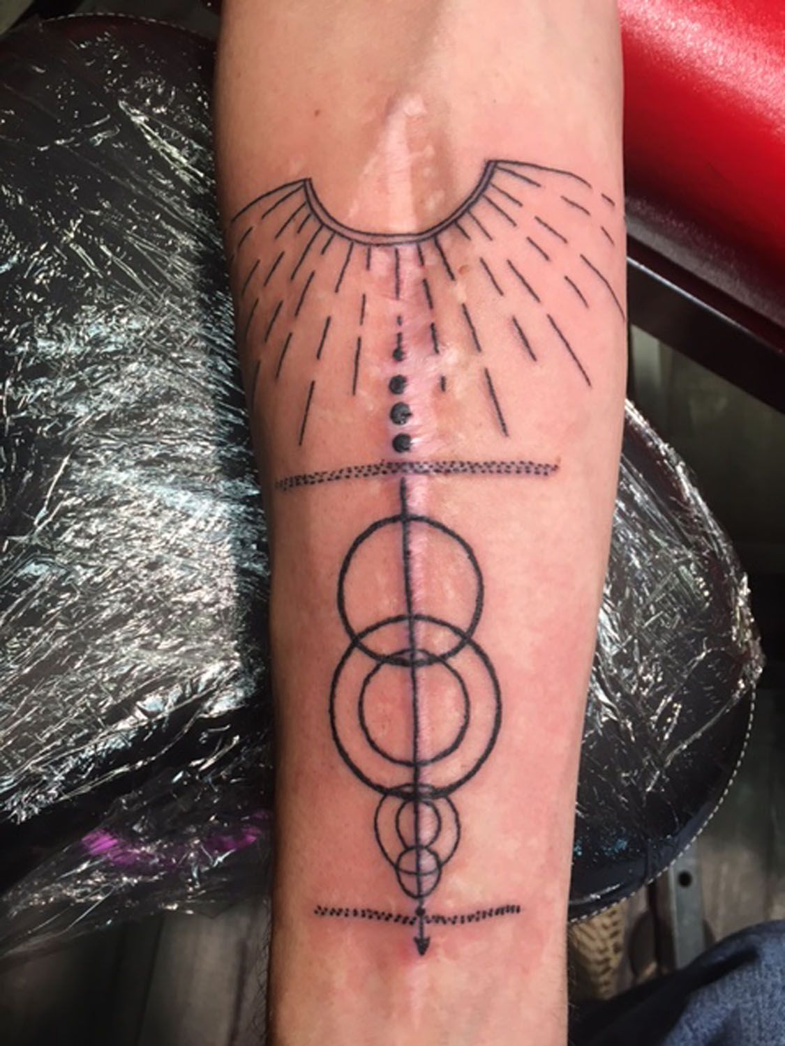 A tattoo on a person 's arm with circles and a cross