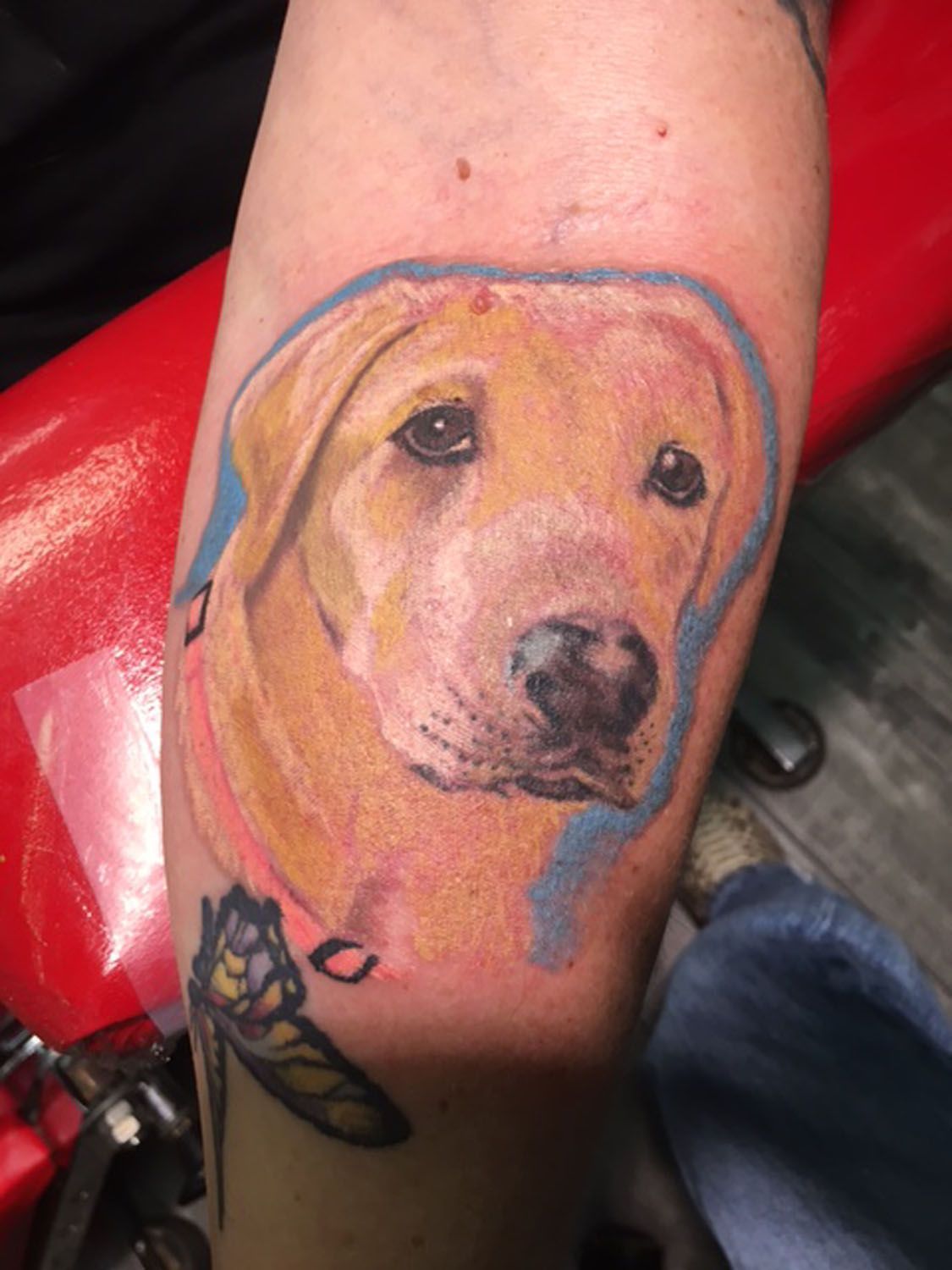A person has a tattoo of a dog on their arm.