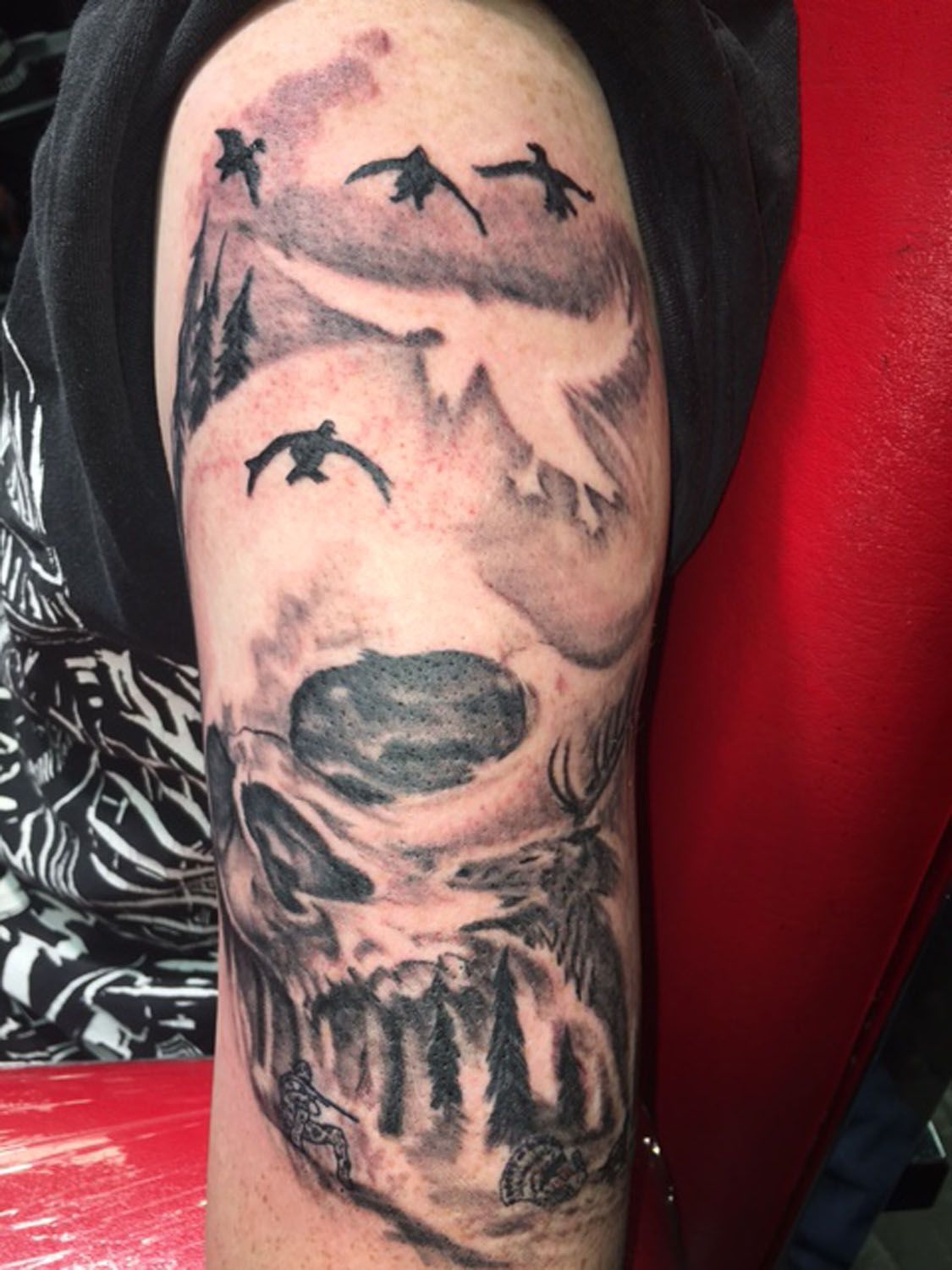 A tattoo of a skull with birds flying around it