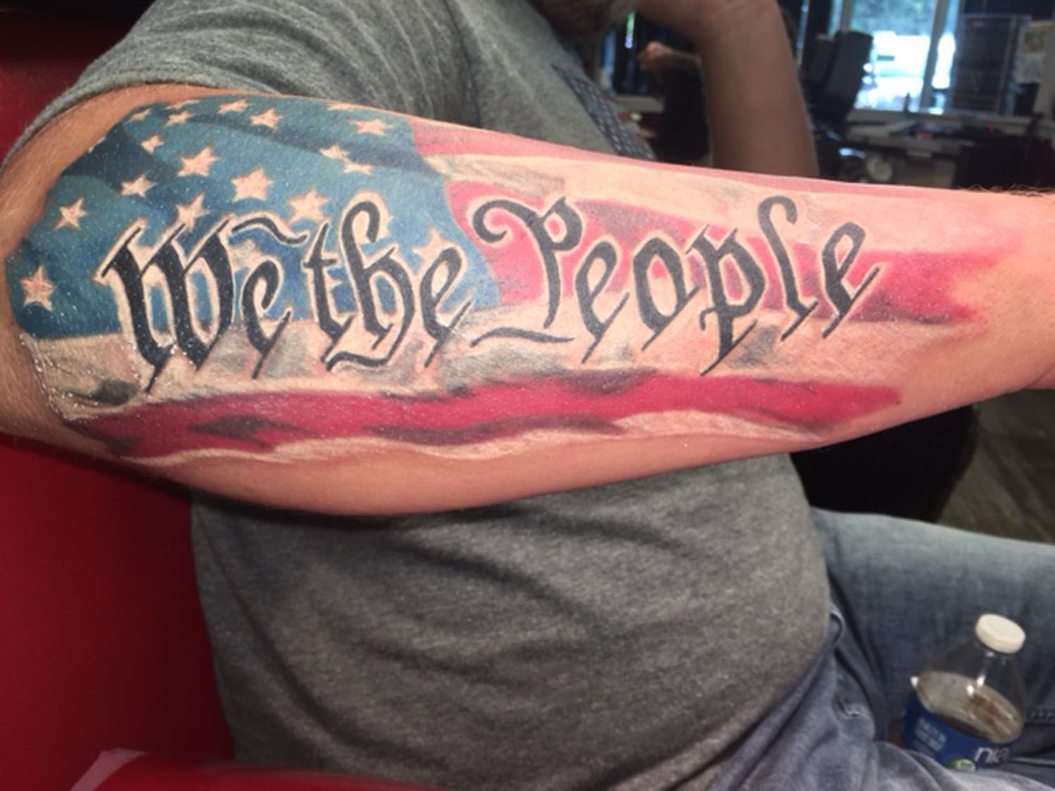 A man has a we the people tattoo on his arm