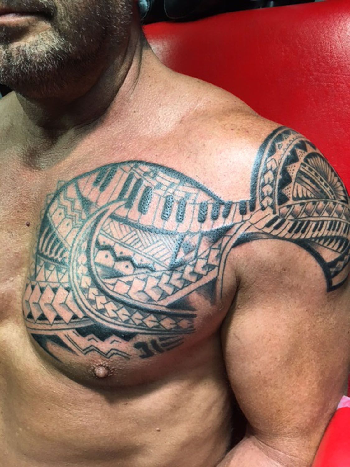 A man with a tattoo on his chest and shoulder.