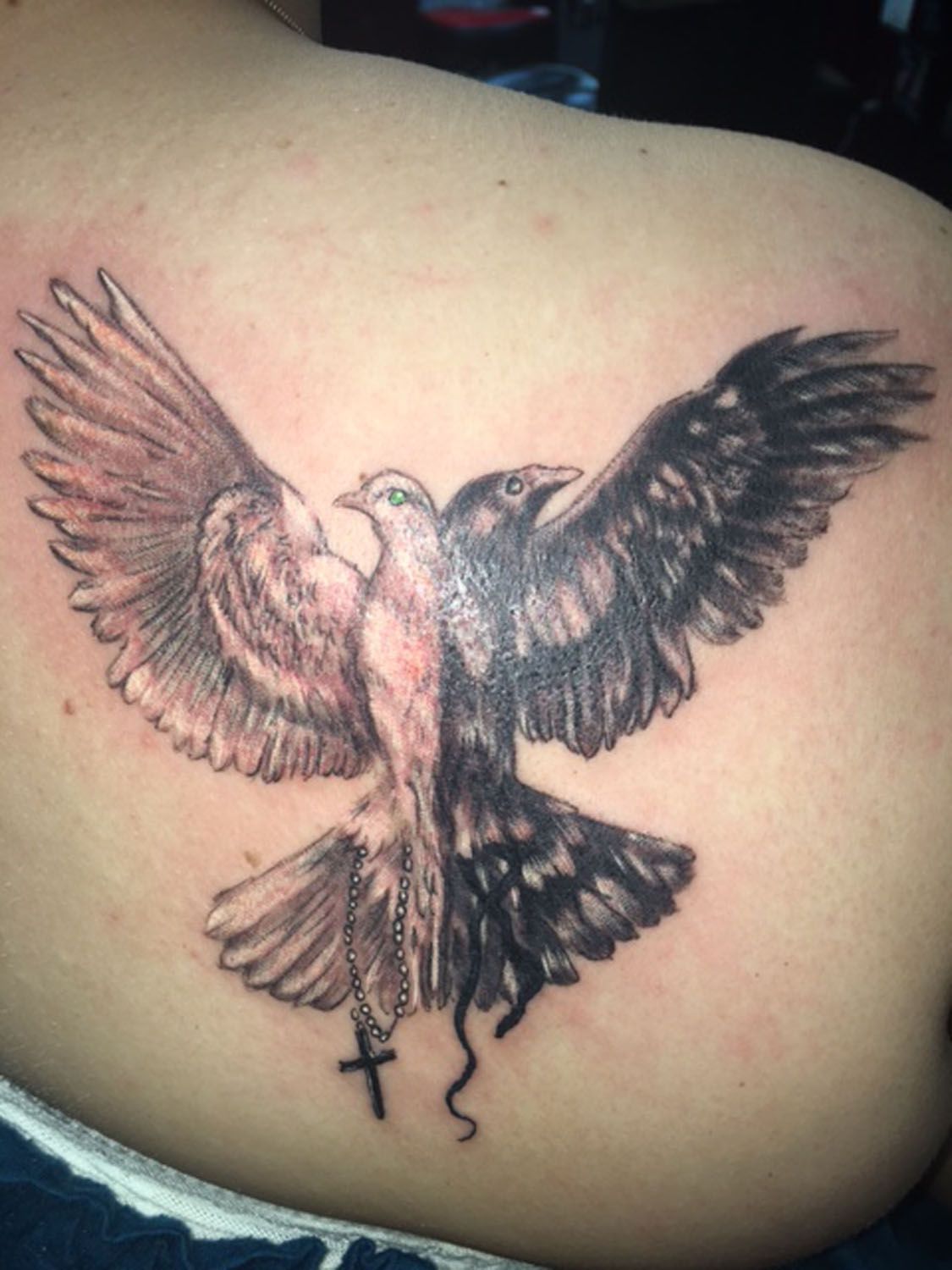 A tattoo of a bird with a cross on its tail