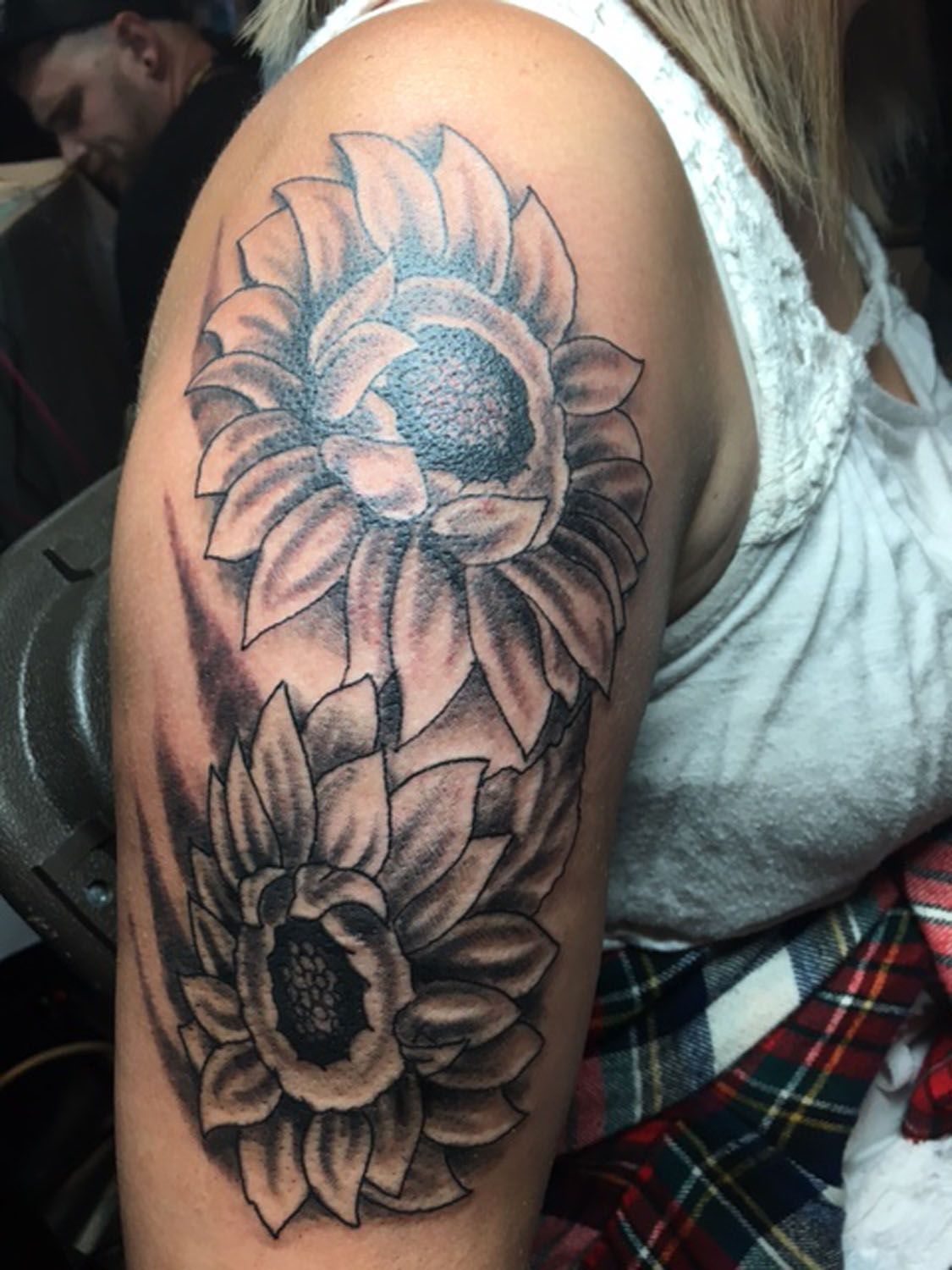 A woman has a tattoo of two sunflowers on her arm