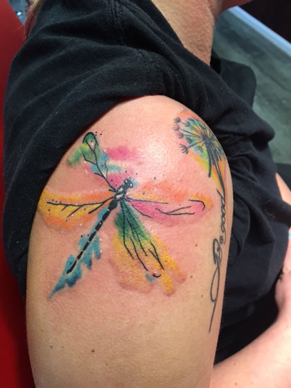 A woman has a dragonfly tattoo on her shoulder.