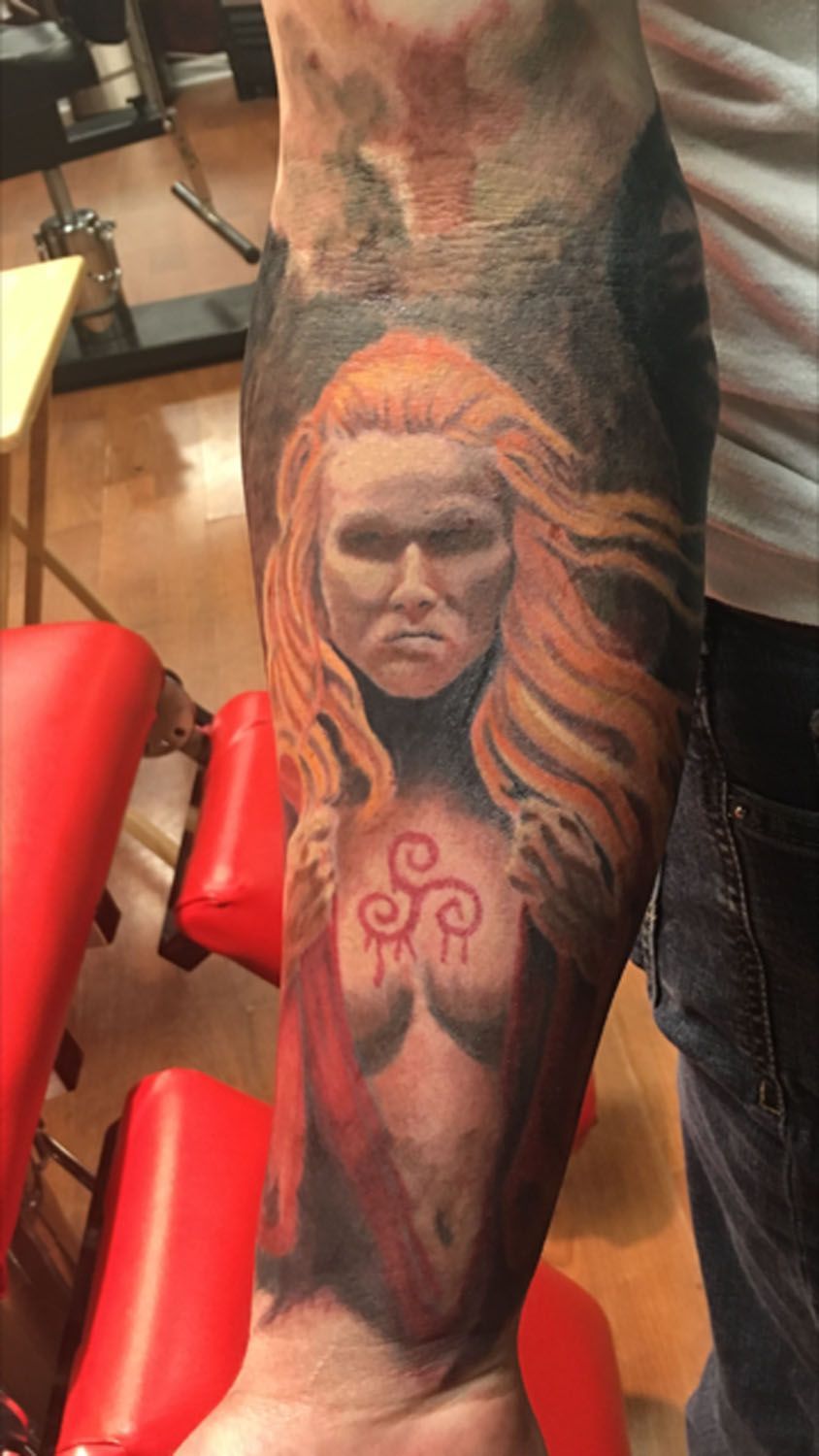 A man has a tattoo of a woman on his arm.