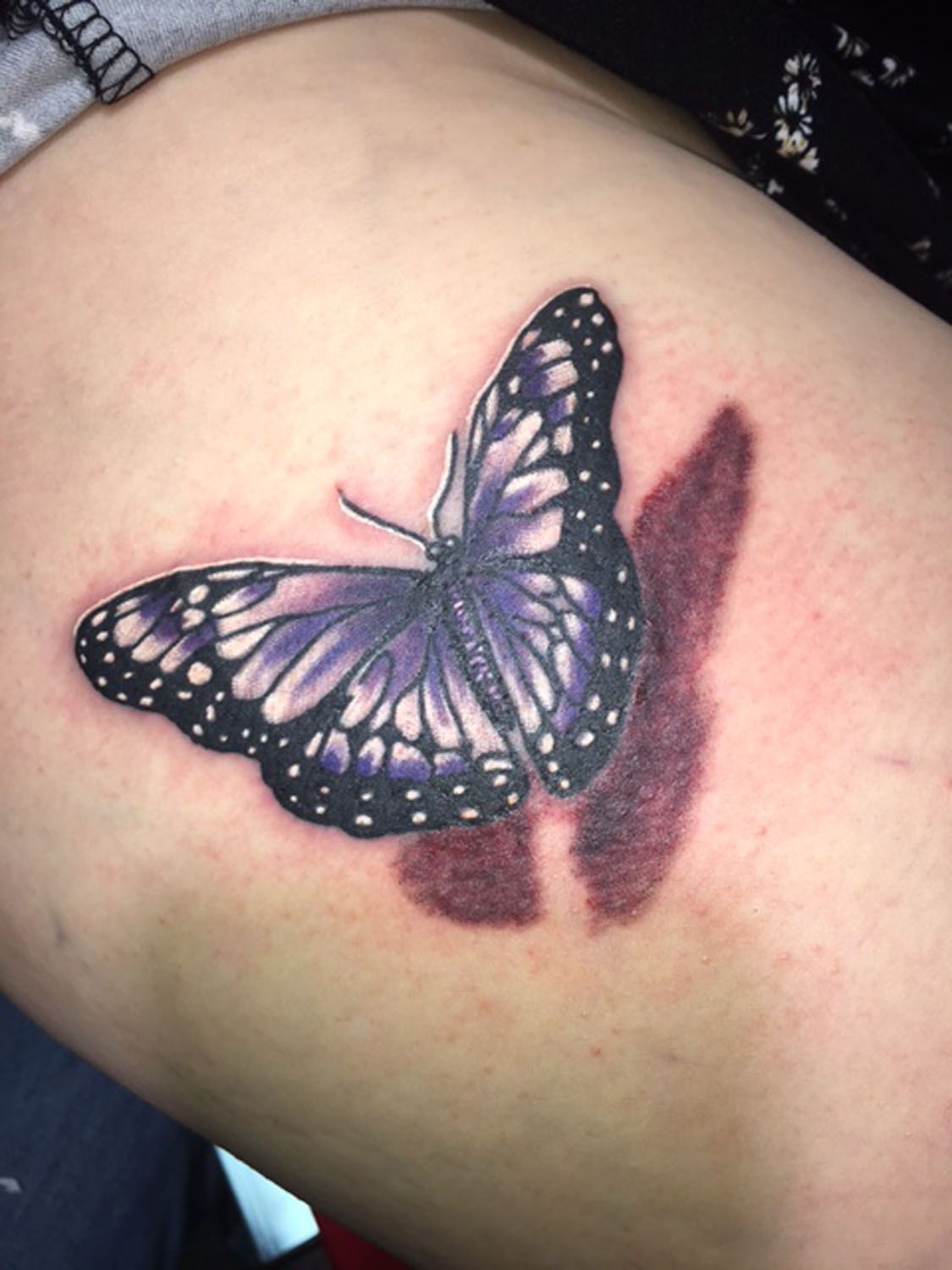 A purple butterfly tattoo on a person 's arm