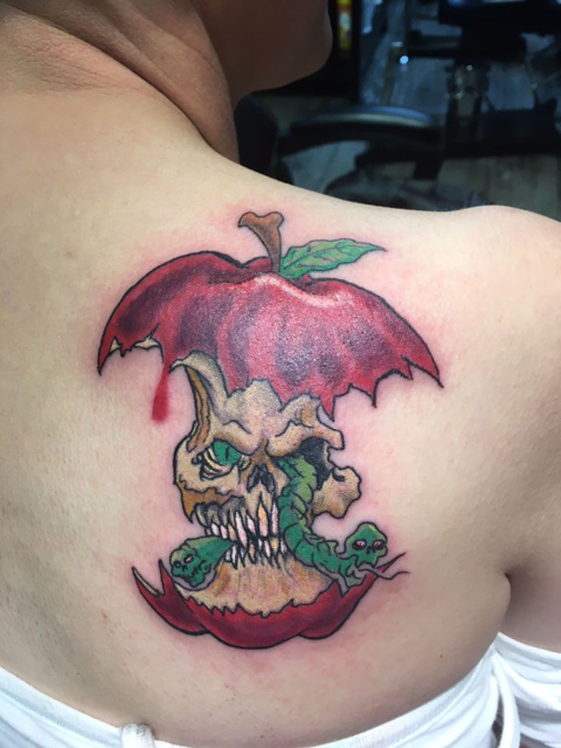 A woman has a tattoo of an apple with a skull in it