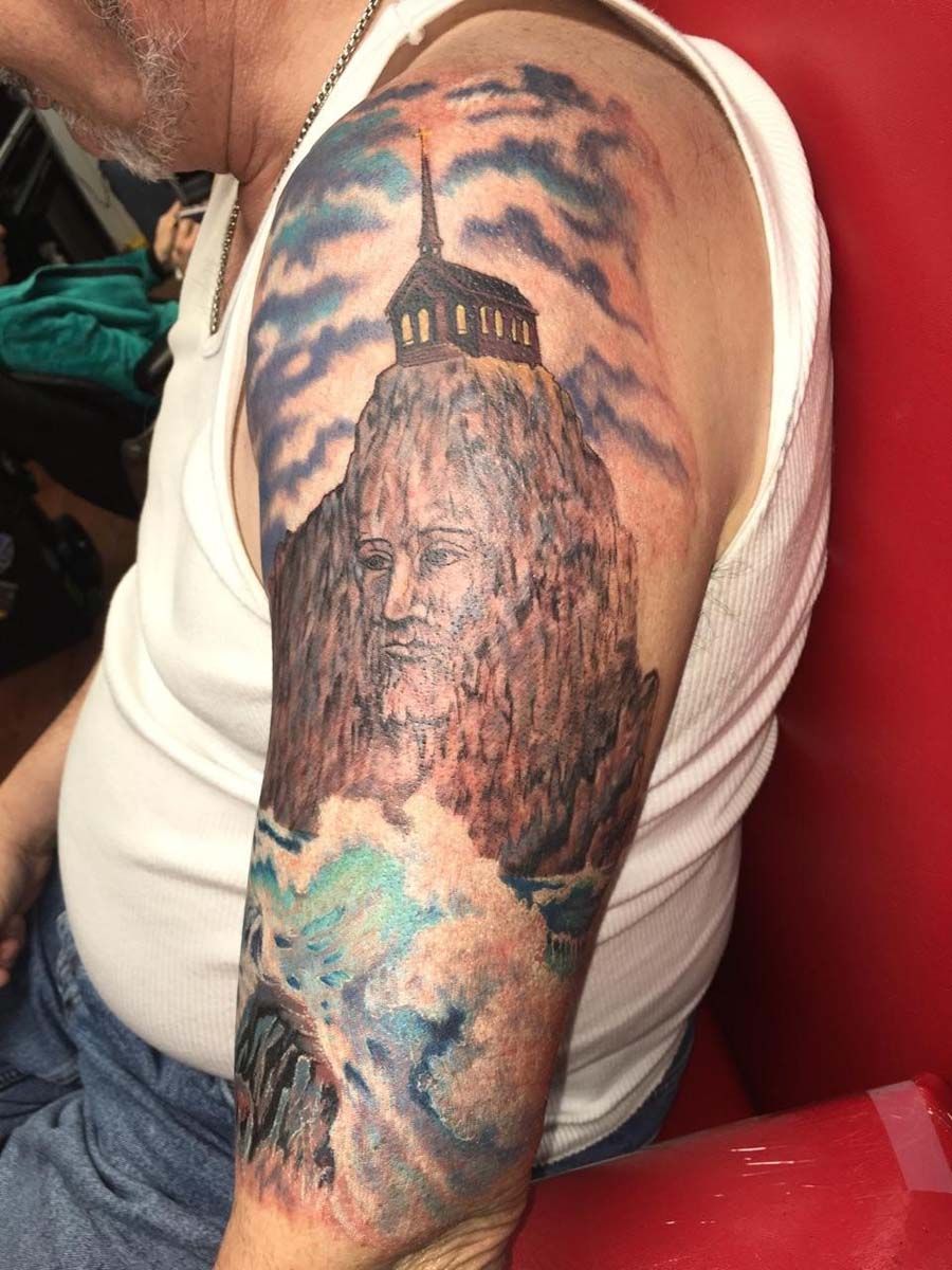 A man has a tattoo of a mountain on his arm.